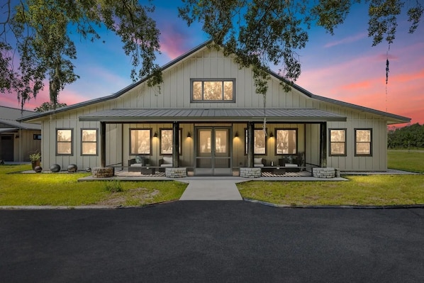 A large, single-story building with a symmetrical facade, a central entrance, and a covered porch area. - Private 10-Acre Ranch Retreat — Sauna & Hot Tub (Morriston)