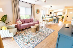 A modern living room with a sofa, chairs, a coffee table, and a dining area with a table and chairs. - Tropical Beach Oasis - Citrus (Cape Canaveral)