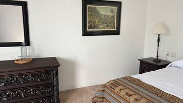 Een slaapkamer met een bed, een kaptafel, een lamp en een lijst met een foto aan de muur.