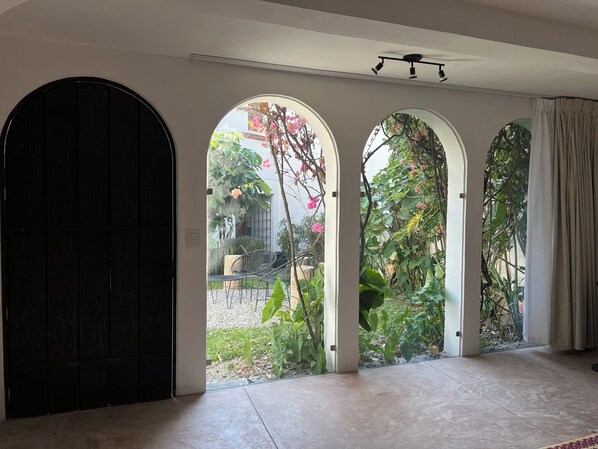 A room with a large black door, three arched windows, and a ceiling fan.