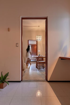 A hallway with a dining area, a potted plant, and a modern chandelier. - Fortaleza II Loft w AC Balcony Near Santo Domingo (Oaxaca)