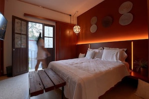 A bedroom with a bed, bedside table, and a view of the outside. - Fortaleza II Loft w AC Balcony Near Santo Domingo (Oaxaca)
