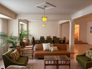 A spacious living area with a sofa, chairs, a coffee table, and a dining table. - Casa Altavista AC Location Terrace Design (Oaxaca)