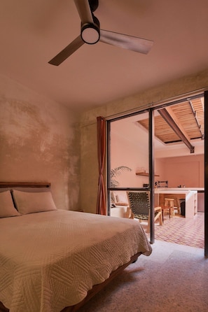 A bedroom with a bed, a ceiling fan, and a sliding glass door leading to a dining area. - Casa Altavista AC Location Terrace Design (Oaxaca)