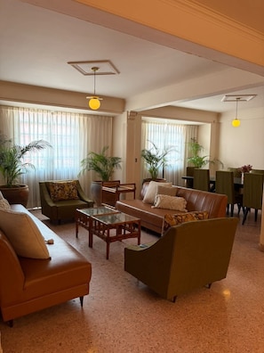A spacious living room with a sofa, armchairs, a coffee table, and a dining area with chairs and a table. - Casa Altavista AC Location Terrace Design (Oaxaca)