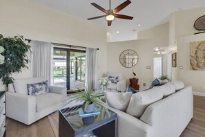 A modern living room with a ceiling fan, a glass coffee table, and a sofa. - The Capes Cozy Corner 1016 SW Cape Pool Home, Gulf Access (Cape Coral)