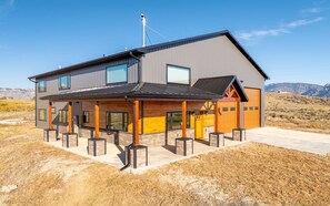 A modern two-story building with a flat roof and a covered patio area. - The Walkin Wyla- newly built barndominum (Cody)