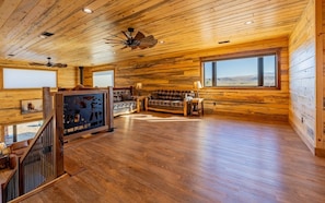 A spacious room with a wooden floor, a sofa, a table, and a ceiling fan. - The Walkin Wyla- newly built barndominum (Cody)
