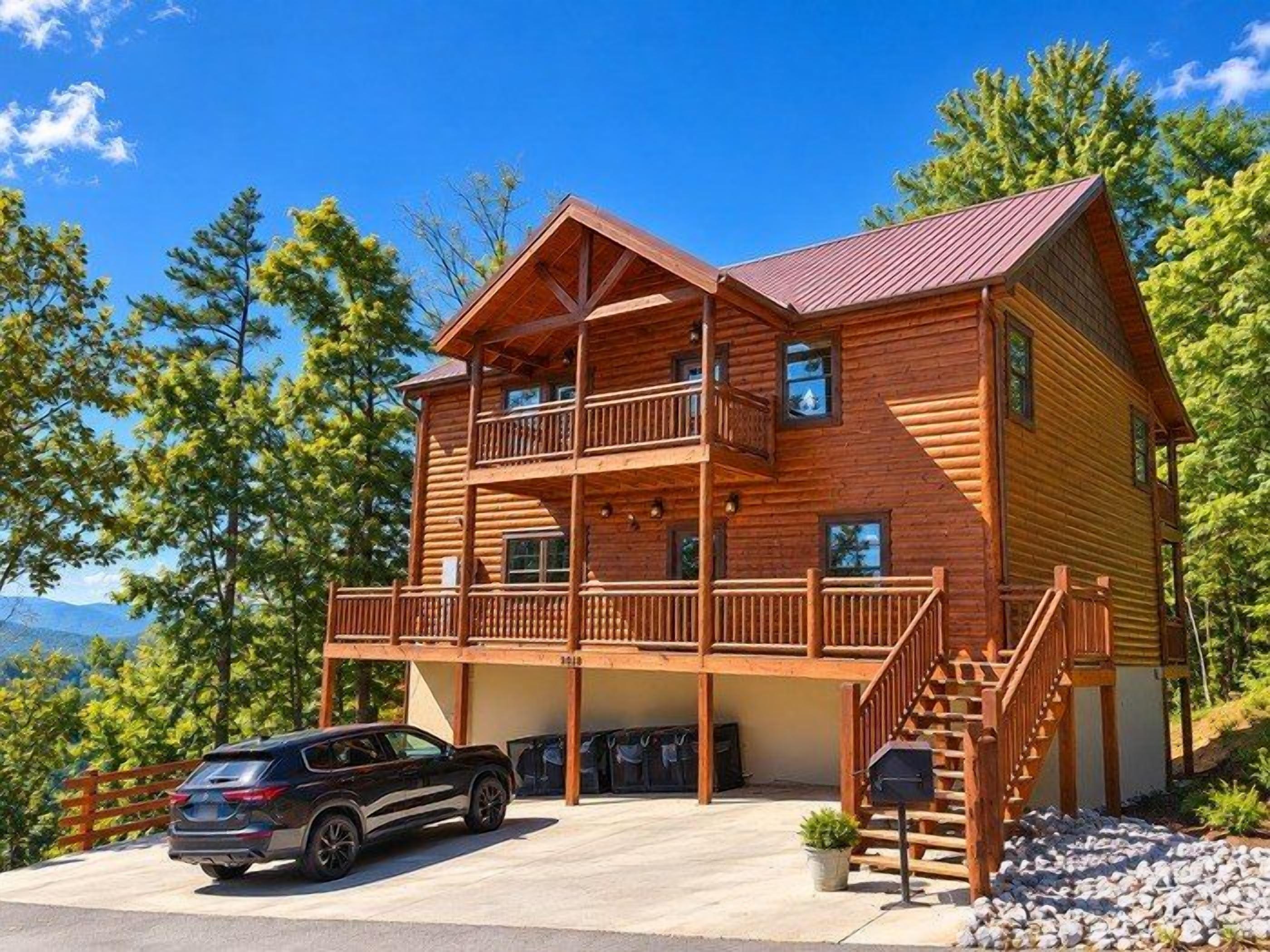 A two-story log cabin with a balcony, a staircase, and a car parked in front.