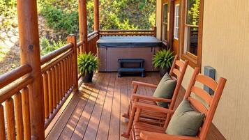 A wooden deck with a hot tub, seating area, and potted plants.