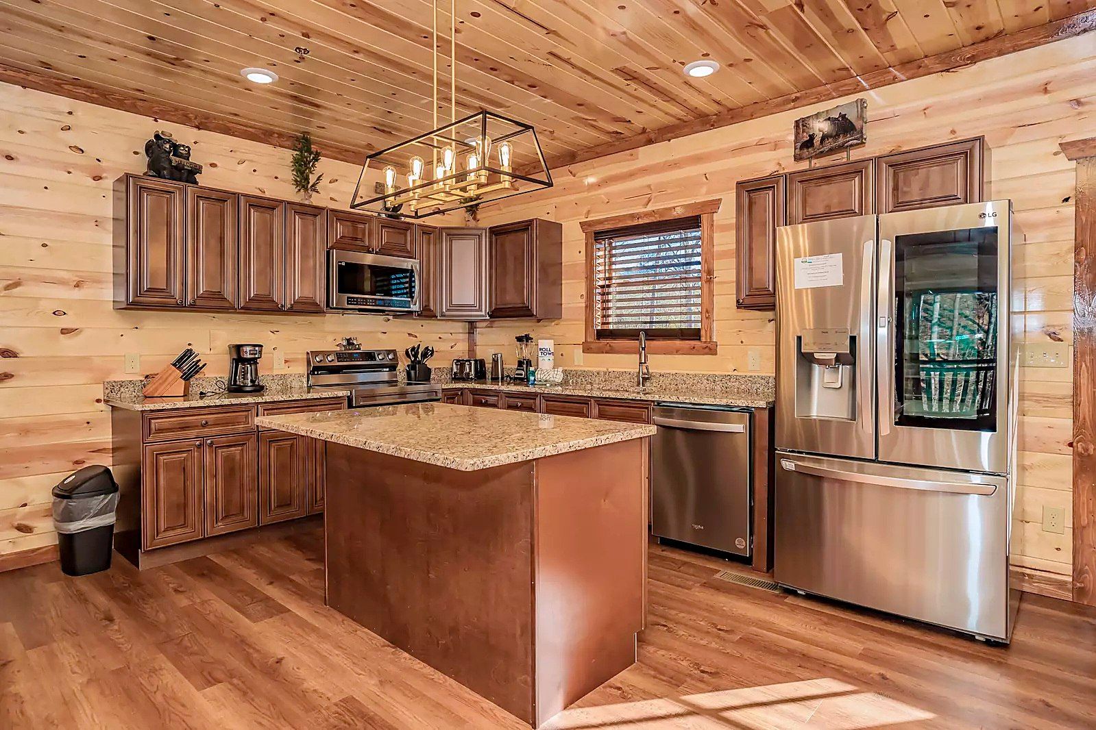 A kitchen with wooden cabinets, stainless steel appliances, a granite countertop, and a central island.