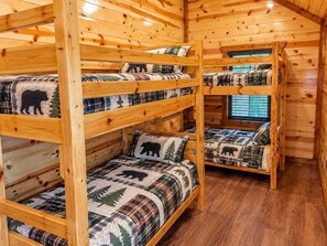 A cabin with bunk beds, each with a bear-themed blanket.