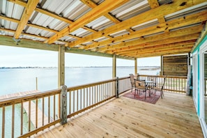 A wooden deck with a railing, a table with chairs, and a view of the water. - The Salt Flat — Waterfront Escape on Salt Lake with Private Pier (Rockport)