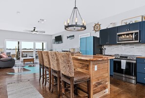 A modern kitchen with a central island, stainless steel appliances, and a view to the outside. - The Salt Flat — Waterfront Escape on Salt Lake with Private Pier (Rockport)