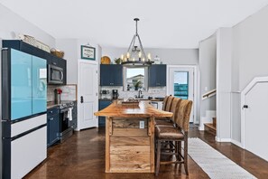 A modern kitchen with a central island, dark cabinetry, and a hanging light fixture. - The Salt Flat — Waterfront Escape on Salt Lake with Private Pier (Rockport)
