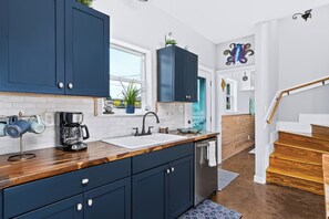 Una cocina moderna con gabinetes azul oscuro, una cafetera y un lavavajillas de acero inoxidable.