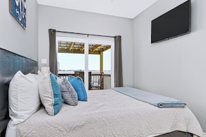 Une chambre à coucher avec un lit, des oreillers, un téléviseur à écran plat et une vue sur l’extérieur.