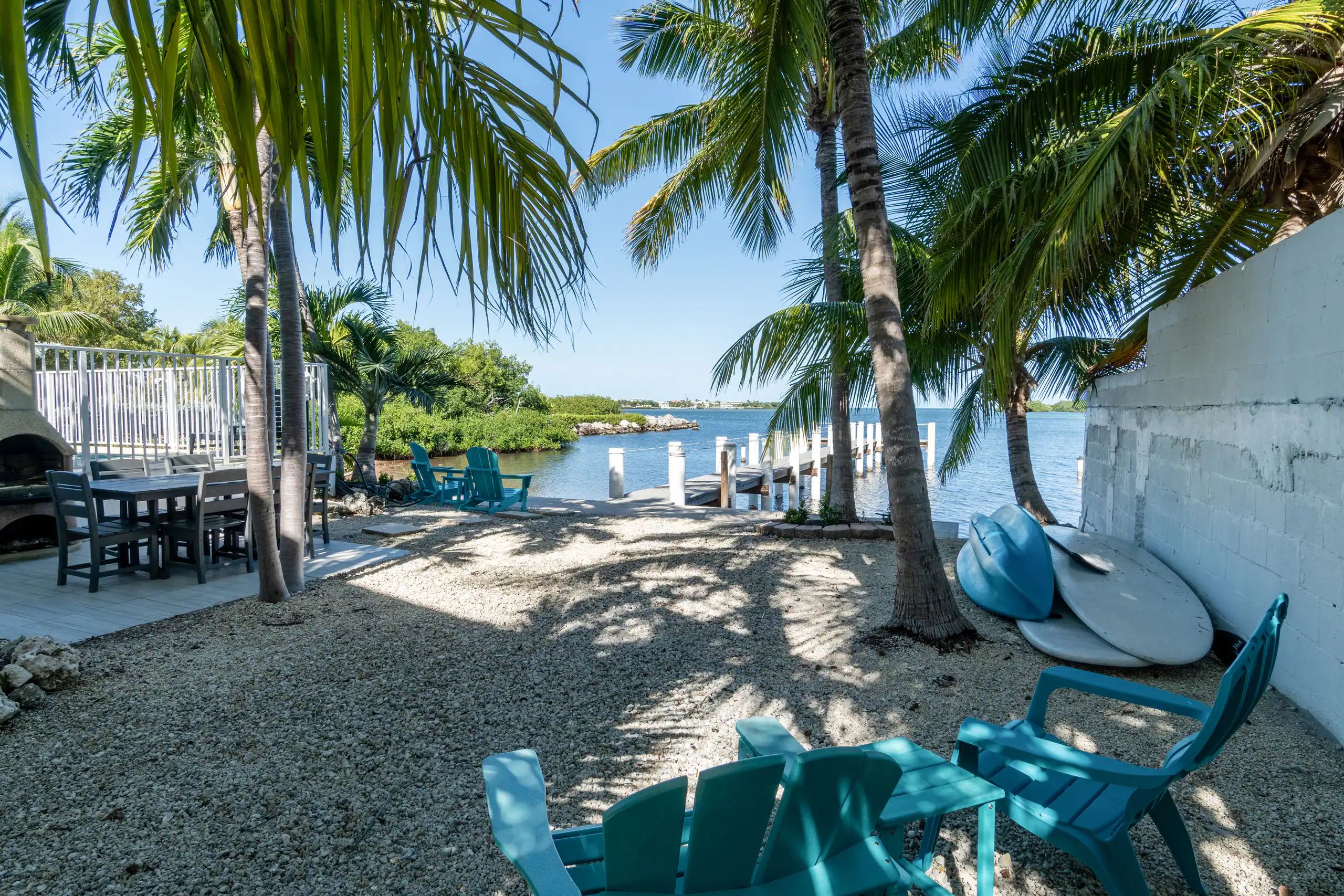A patio area with a table and chairs, a grill, and a view of the water.
