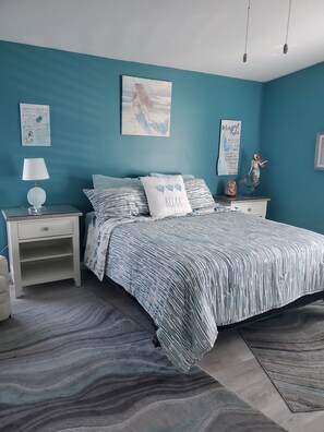 Ein Schlafzimmer mit einem Bett, Nachttischen, einer Lampe und Wandbildern.