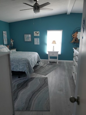 A bedroom with a bed, a nightstand, a dresser, and a ceiling fan. - Cozy 2-bedroom waterfront manufactured home on Spring Creek with gulf access. (Bonita Springs)