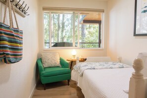A room with a bed, a green chair, a window with a view of trees, and a hanging bag. - WATERFRONT 4bd, 3.5ba Home w/ Private Dock, Hot Tub, Gas Fire Pit, 2 King Beds (Shelton)
