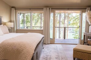 A hotel room with a large bed, a desk, a chair, a balcony, and a view of trees. - WATERFRONT 4bd, 3.5ba Home w/ Private Dock, Hot Tub, Gas Fire Pit, 2 King Beds (Shelton)