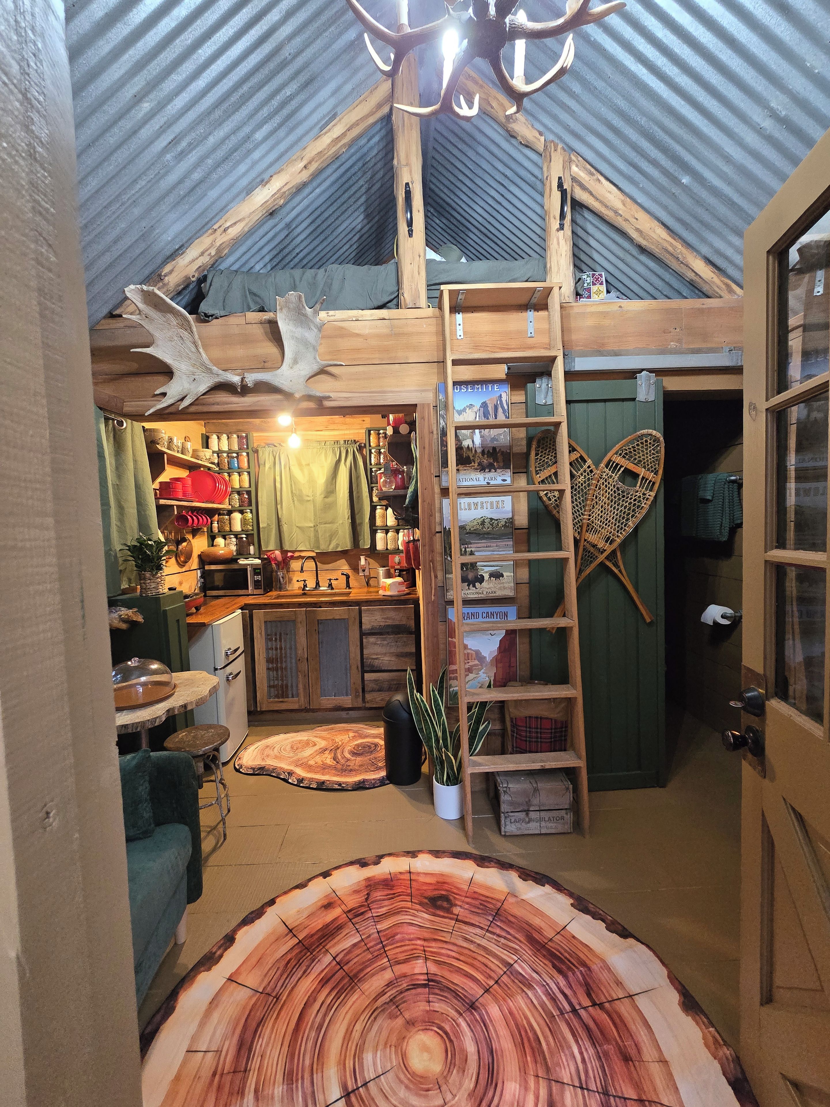 A rustic interior with a wooden ceiling, a ladder, and a large wooden table with a tree ring design.