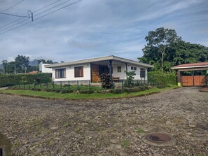 A single-story house with a covered porch, a fenced yard, and a rocky ground surface. - New Listing (Provincia de Alajuela)