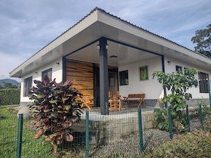 A modern house with a covered porch, a wooden bench, and a potted plant. - New Listing (Provincia de Alajuela)