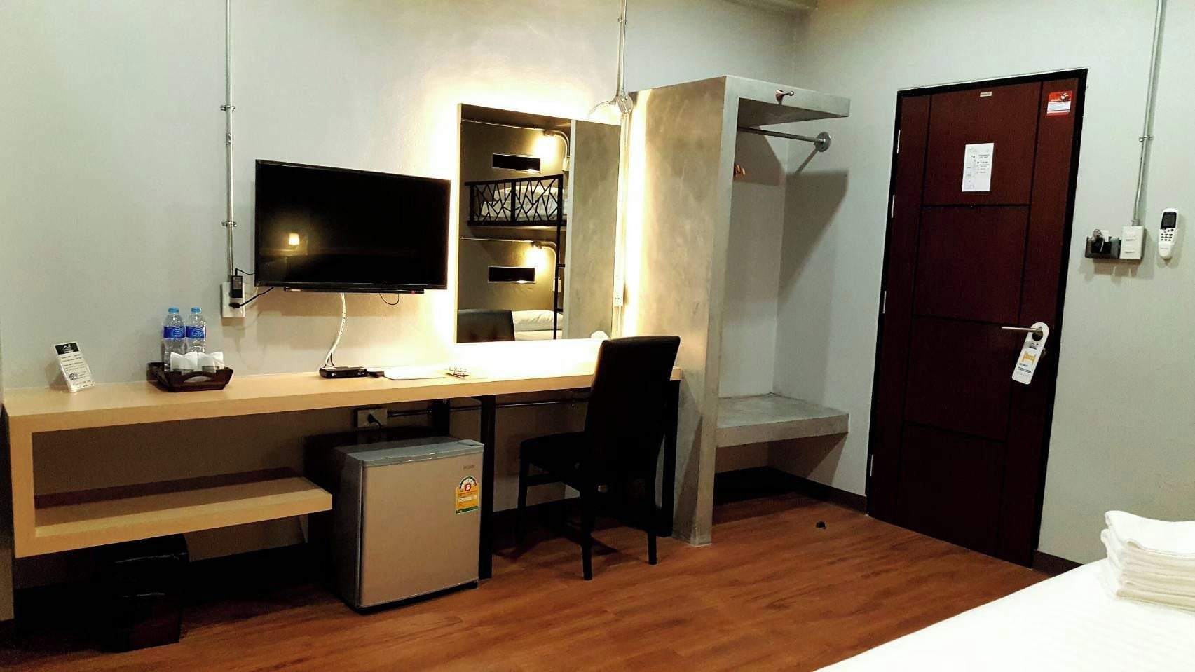 Hotelkamer met een bed, een bureau met een computer, een televisie, een minibar en een douche.