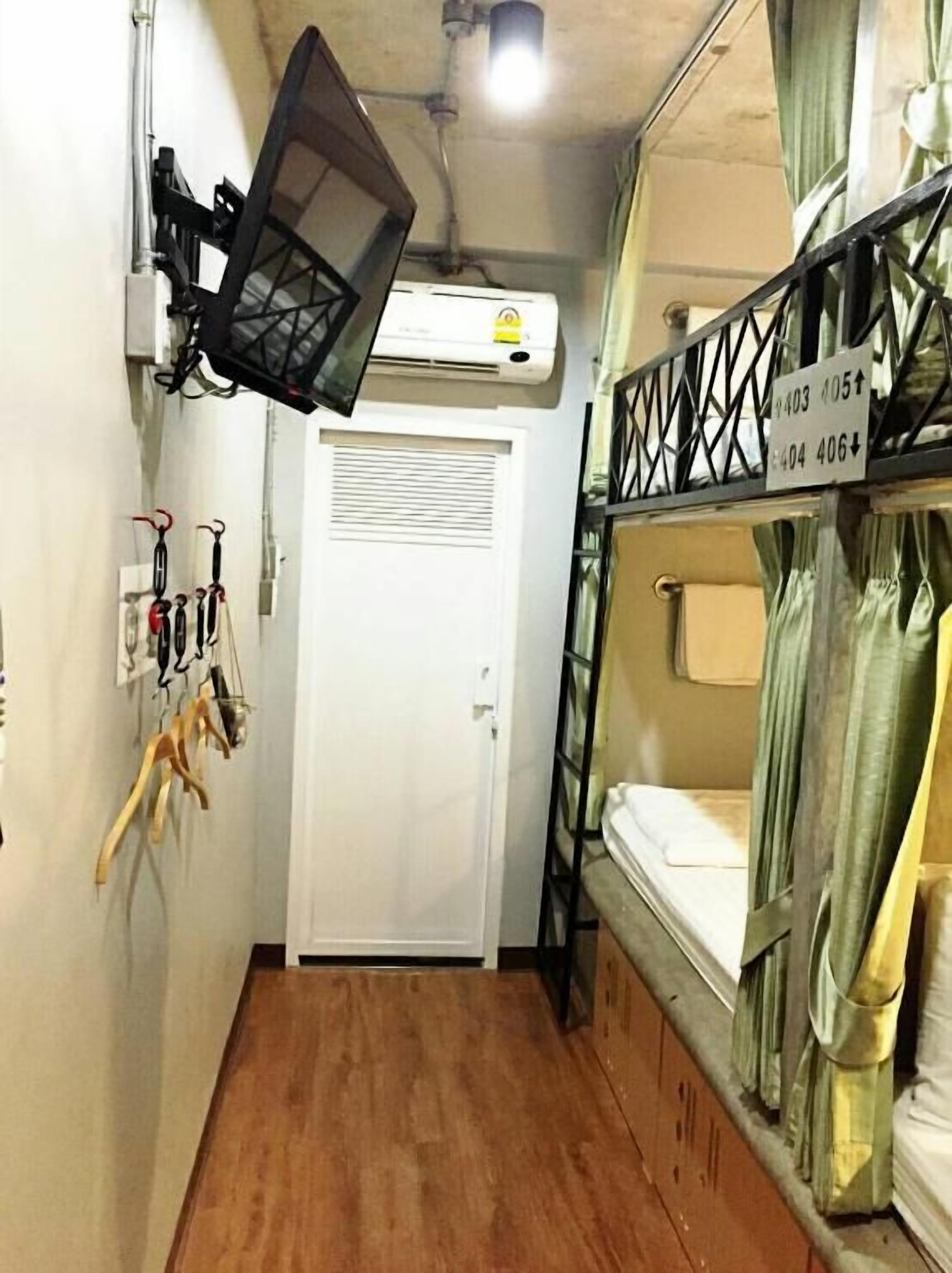 A narrow corridor with bunk beds on one side, a white door, and a mounted air conditioner.