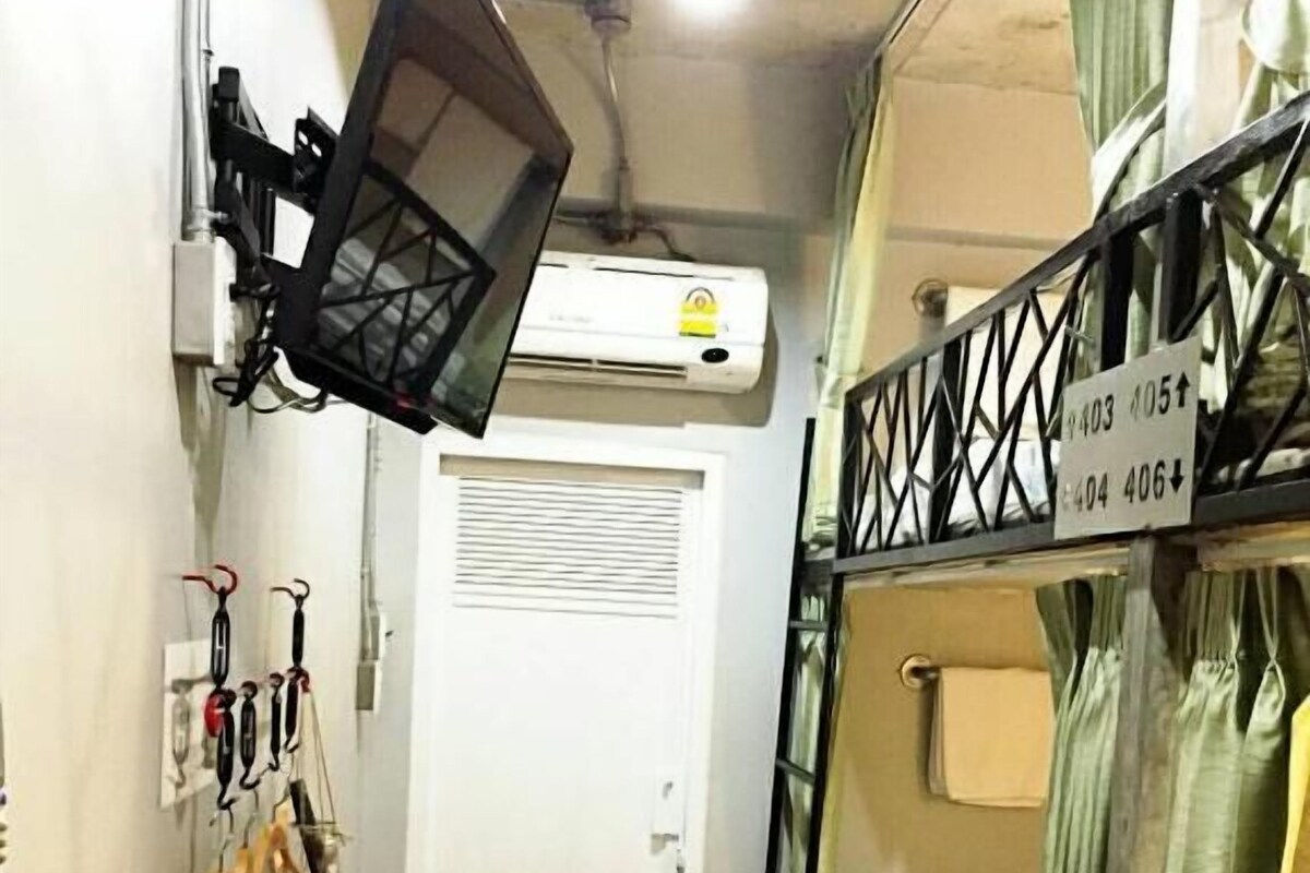 A narrow corridor with bunk beds on one side, a white door, and a mounted air conditioner.