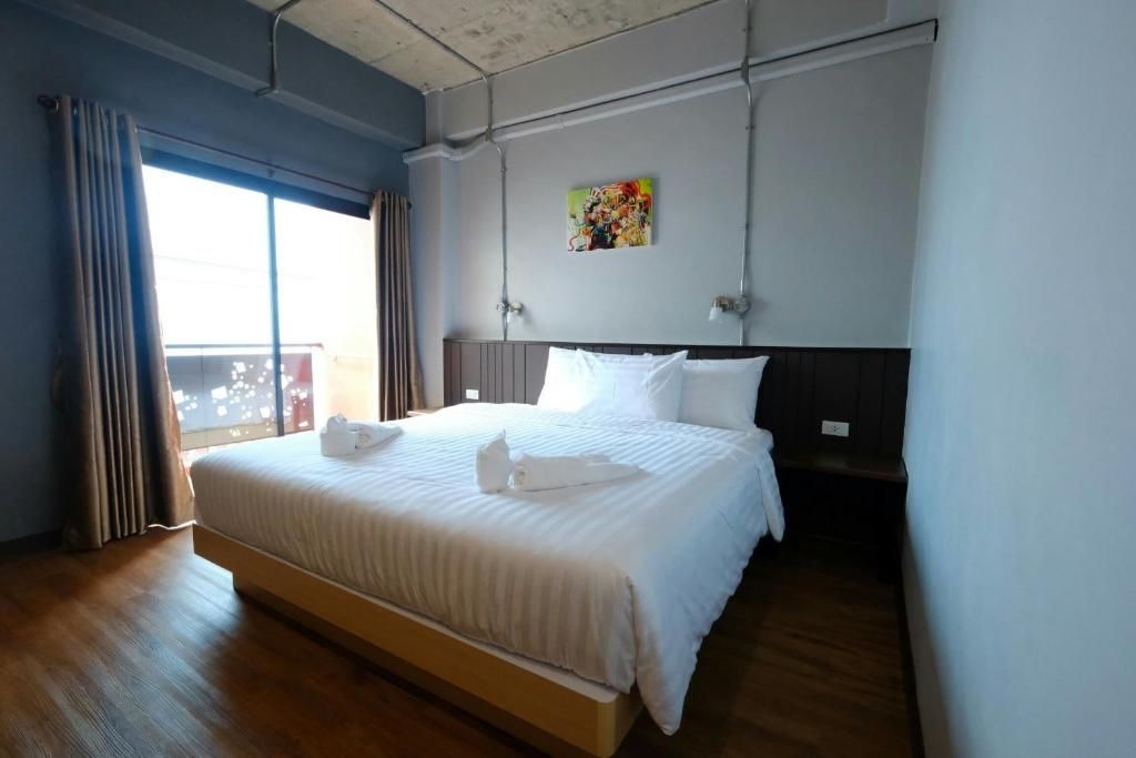 Een hotelkamer met een groot bed, een schilderij aan de muur en uitzicht door het raam.