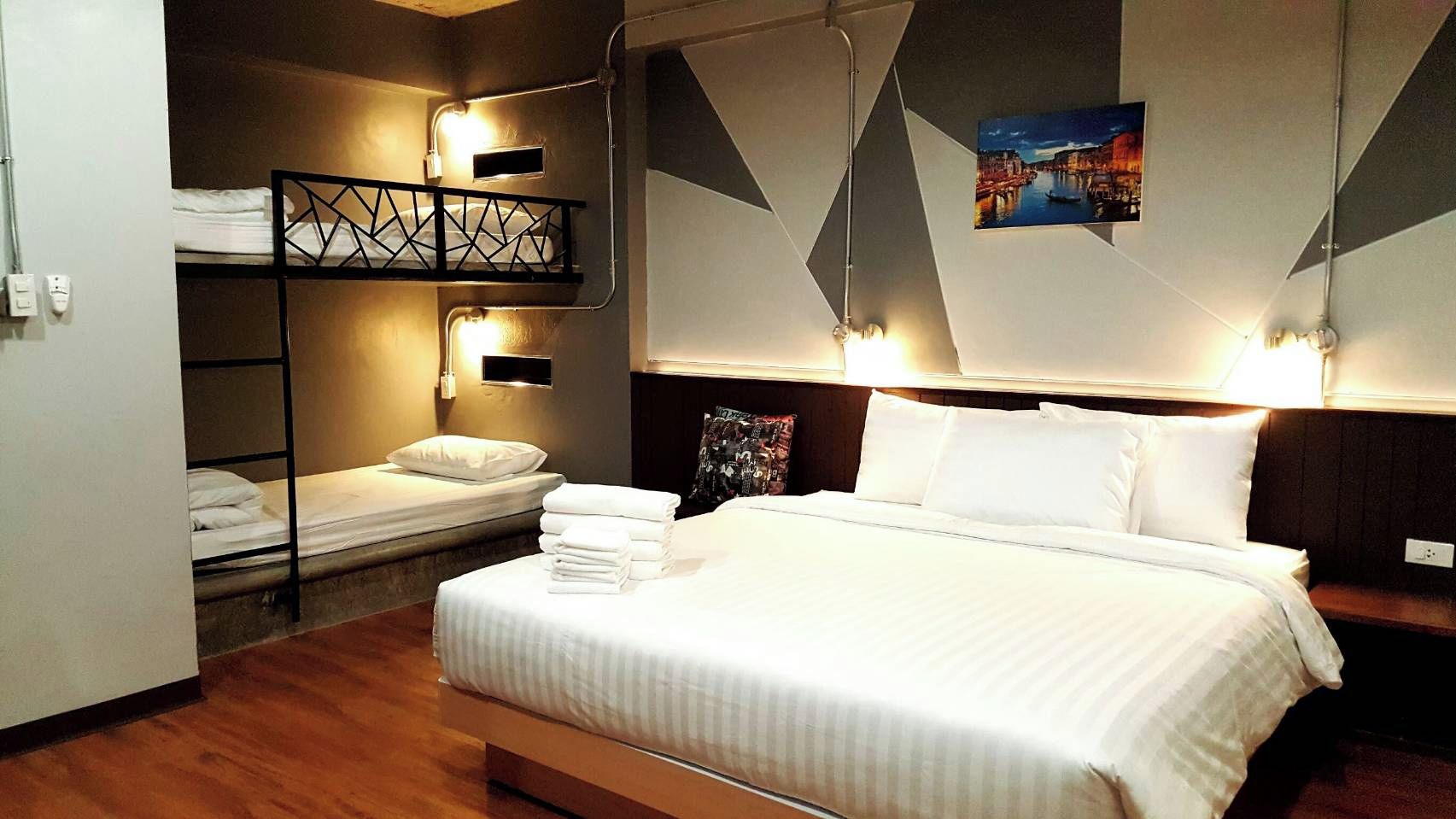 A hotel room with a large bed, a bunk bed, and a wall-mounted picture.