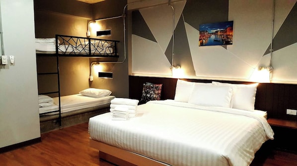 A hotel room with a large bed, a bunk bed, and a wall-mounted picture. - Room2u (Hat Yai)