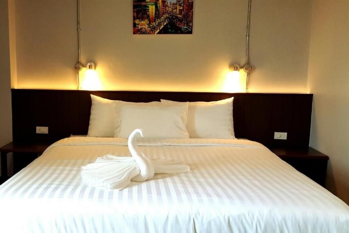 A hotel room with a large bed, two bedside tables, and a headboard with wall-mounted lights.