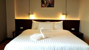 A hotel room with a large bed, two bedside tables, and a headboard with wall-mounted lights. - Room2u (Hat Yai)