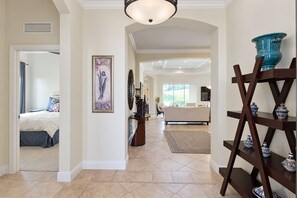 A spacious hallway with a bed, a framed artwork, a mirror, and a decorative shelf with pottery. - Serene University Park Golf & Country Club Pool Home - Gulf Standard (Bradenton)