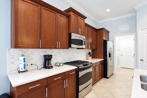 A modern kitchen with wooden cabinets, stainless steel appliances, and a white countertop. - Serene University Park Golf & Country Club Pool Home - Gulf Standard (Bradenton)