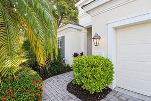 A residential property with a paved driveway, a garage door, and a well-maintained garden with various plants and shrubs. - Serene University Park Golf & Country Club Pool Home - Gulf Standard (Bradenton)