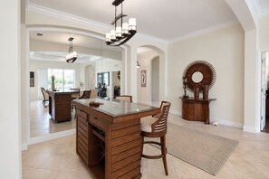 A spacious kitchen with a central island, wooden cabinetry, and a large mirror above the island. - Serene University Park Golf & Country Club Pool Home - Gulf Standard (Bradenton)