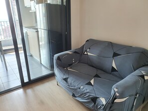 A modern living room with a sofa, a glass door leading to a balcony, and a kitchen area visible through the glass. - 10 minutes to BTS bangna and river near true digital park and bitec 3 pools 2 gy (Krung Thep Maha Nakhon)