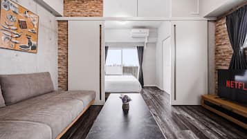 Una sala de estar moderna con un sofá, una mesa de centro con un florero, un televisor y una pared de ladrillo.