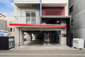 A multi-level parking garage with concrete pillars, a red and white awning, and a white air conditioning unit. - J-STAR 802 (Sapporo)