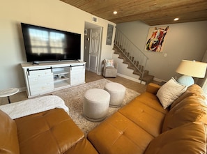 A living room with a television, sofa, ottomans, and a staircase. - Oxford Condo ~ Walk to Campus (Oxford)