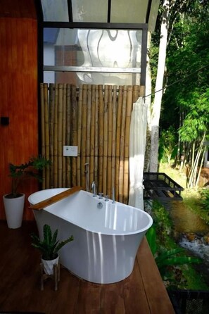 A modern bathroom with a freestanding bathtub, bamboo privacy screen, and potted plants. - Chertarn Homestay (Doisaket)