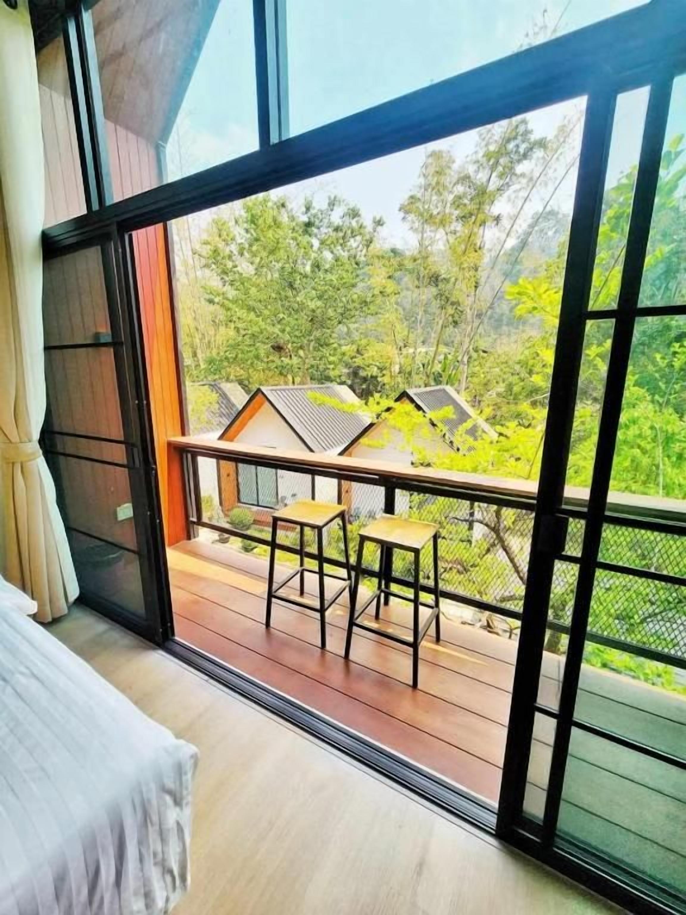 A room with a large window, a bed, and a small table with chairs.