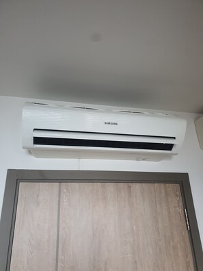 Eine weiße Klimaanlage ist an einer Wand oberhalb einer Holztür angebracht.