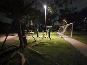 Un'area esterna con attrezzature per esercizi, un pallone da calcio e un percorso pavimentato.