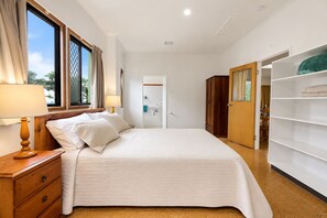 Habitación de hotel con cama, mesitas de noche, armario y baño visible a través de una puerta abierta.